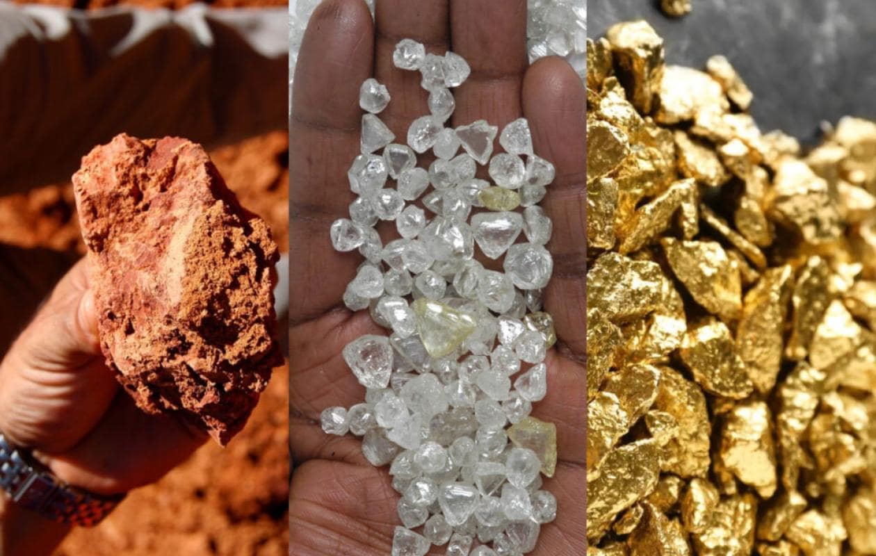 Aerial view of a massive, red open-pit bauxite mine contrasting sharply with surrounding green forests in Guinea.